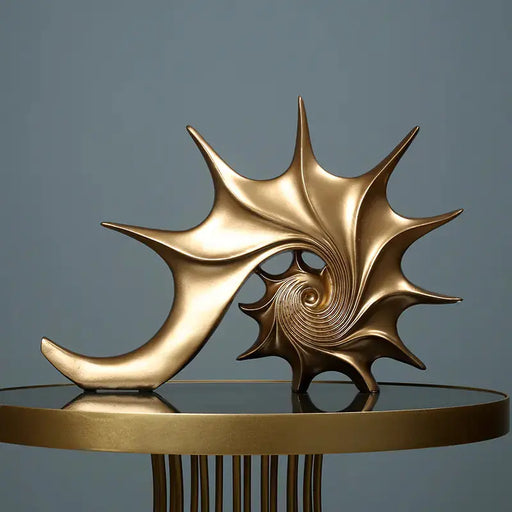 Gold shell sculpture on a reflective surface with a gray background