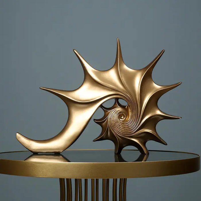 Gold shell sculpture on a reflective surface with a gray background