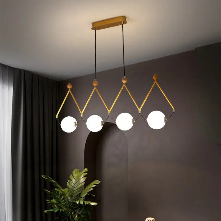 Modern pendant light fixture with four round lights in a room with dark walls and a plant.