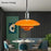Orange pendant light in a modern dining room with gray walls and colorful chairs.